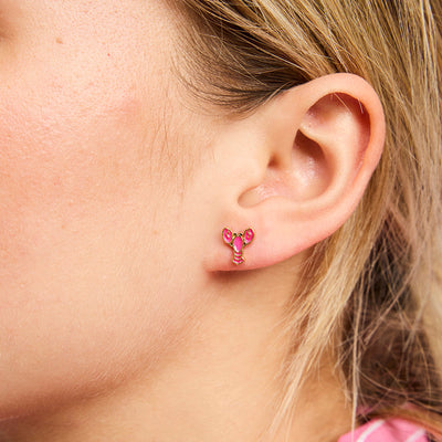 Close-up of an ear wearing pink heart-shaped earrings.