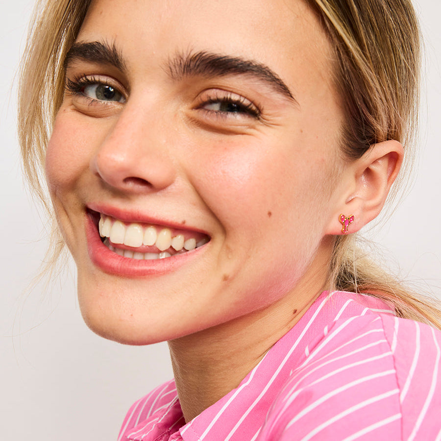 Woman wearing a pink striped shirt with a plain background with Tiger Tree Lobster earrings