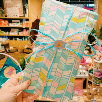 Gift bag with a colourful pattern held in front of a store interior.