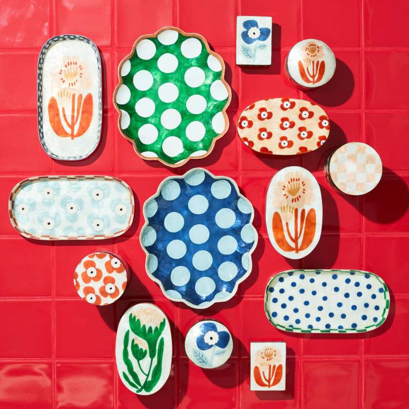 Collection of colorful ceramic plates and coasters on a red tiled background