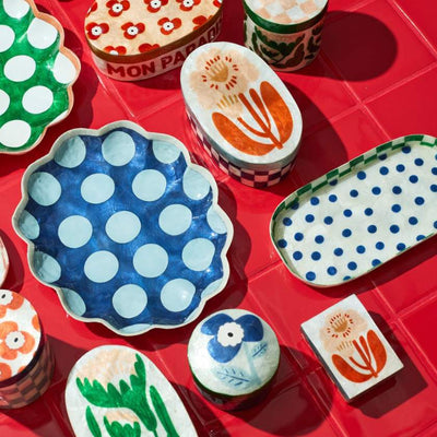 Colorful ceramic plates with floral and polka dot patterns on a red surface.