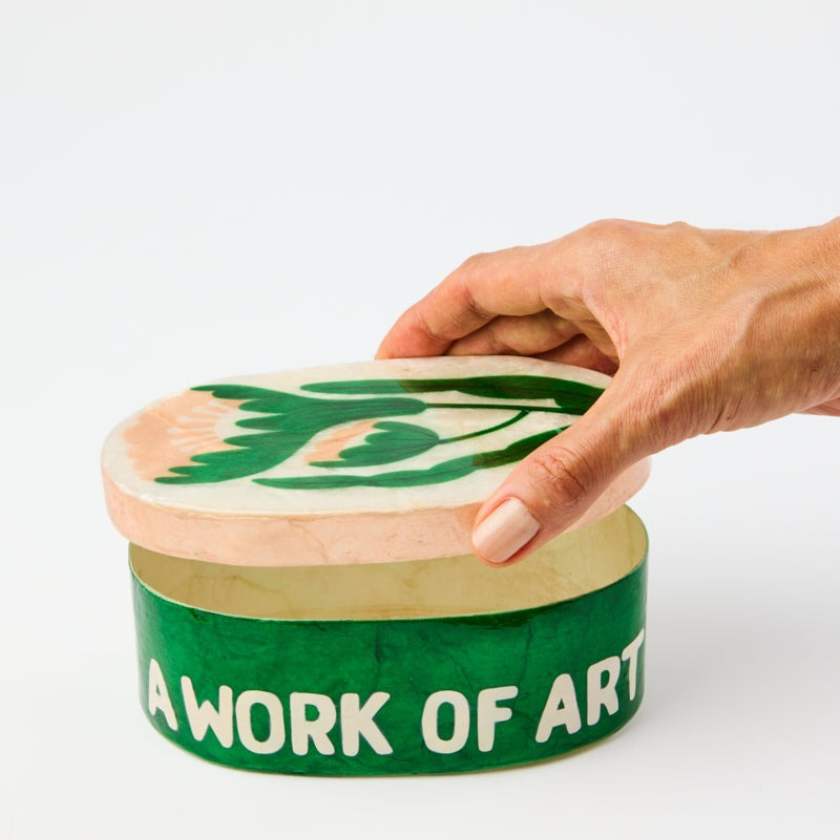 Hand holding a decorative box with 'A Work of Art' text on a white background