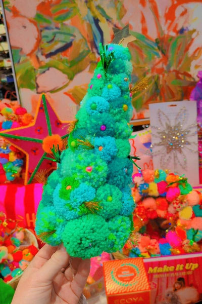Colorful pom-pom tree held by a hand with a vibrant, multicolored background. | Pom pom wreaths and christmas trees by Arissa Lifestyle available at Zebra Finch in Newcastle, NSW