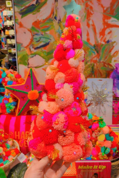Colorful pom-pom tree held by a hand with a vibrant, multicolored background. | Pom pom wreaths and christmas trees by Arissa Lifestyle available at Zebra Finch in Newcastle, NSW