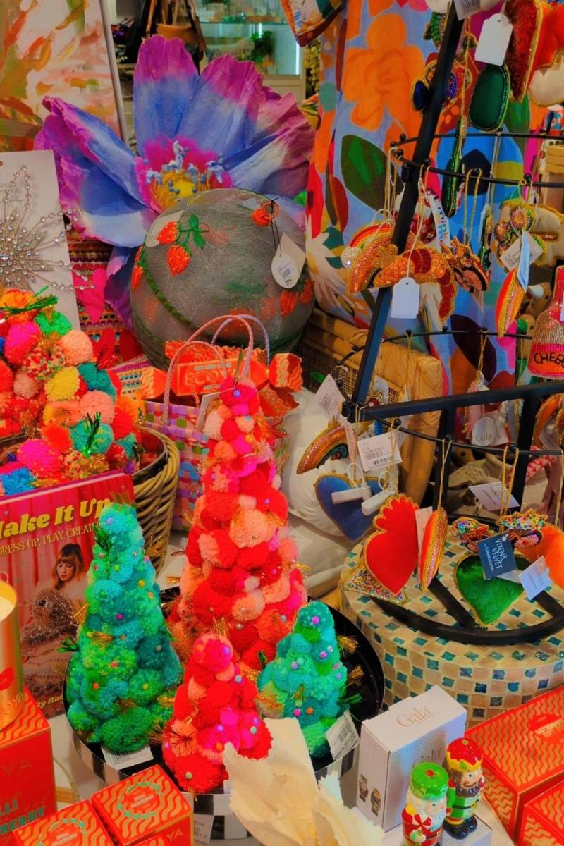 Colorful pom-pom tree held by a hand with a vibrant, multicolored background. | Pom pom wreaths and christmas trees by Arissa Lifestyle available at Zebra Finch in Newcastle, NSW