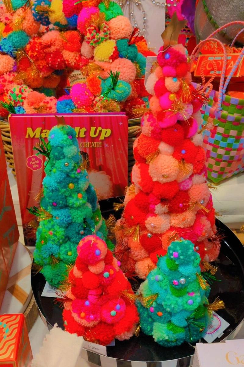 Colorful pom-pom tree held by a hand with a vibrant, multicolored background. | Pom pom wreaths and christmas trees by Arissa Lifestyle available at Zebra Finch in Newcastle, NSW