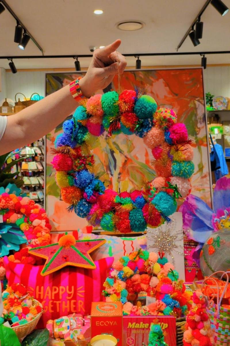 Colorful pom-pom wreath against a vibrant floral backdrop | Arissa pom pom wreaths available at Zebra Finch