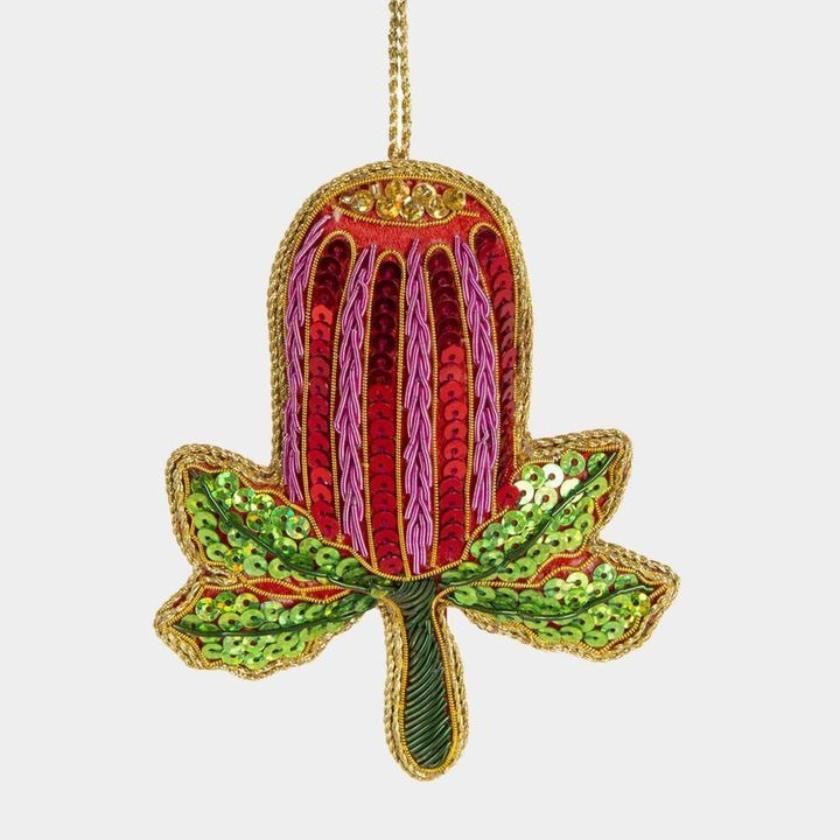 Decorative ornament shaped like a flower with red center and green leaves on a white background
