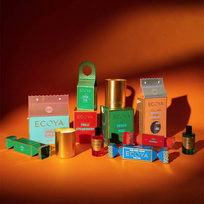 Collection of Ecoya products including candles and boxes on an orange background