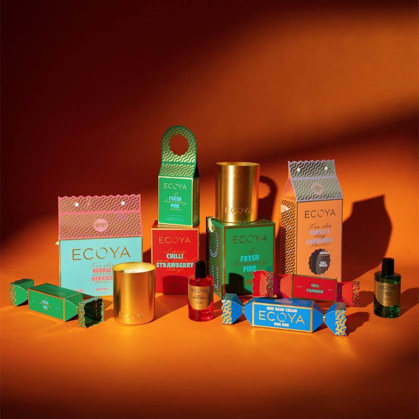Collection of Ecoya products including candles and boxes on an orange background