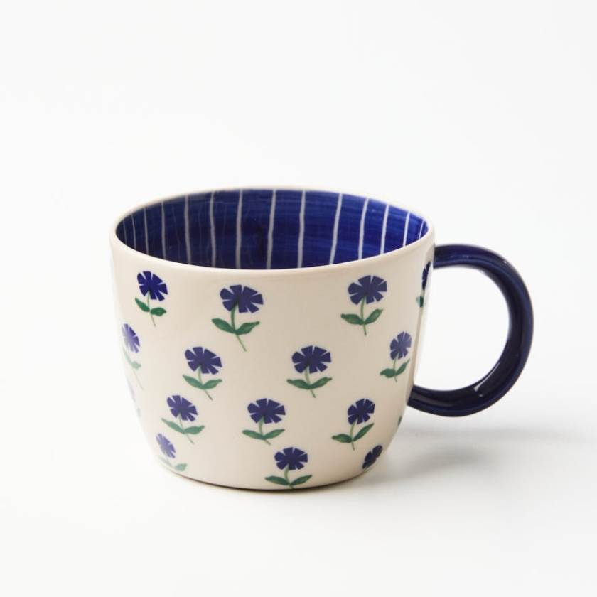 Ceramic mug with floral pattern and blue interior on a white background