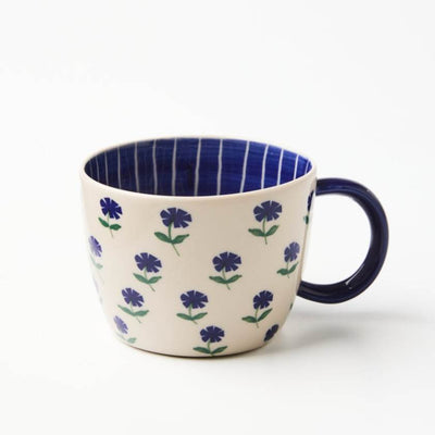 Ceramic mug with floral pattern and blue interior on a white background