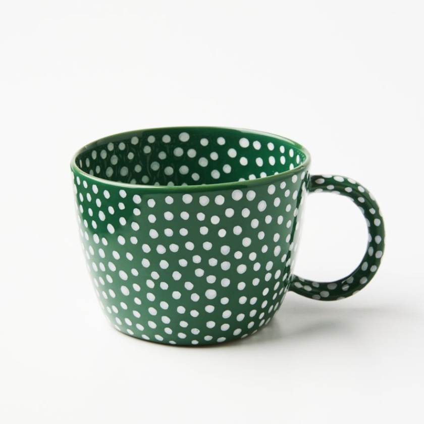 Green mug with white polka dots on a white background