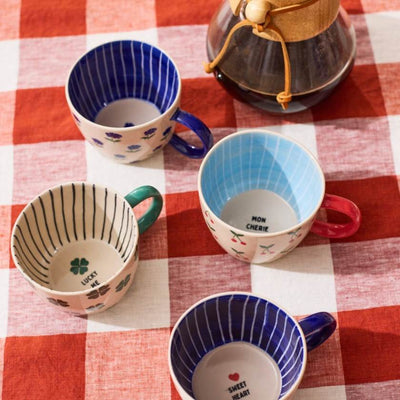Set of colorful mugs on a red and white checkered tablecloth