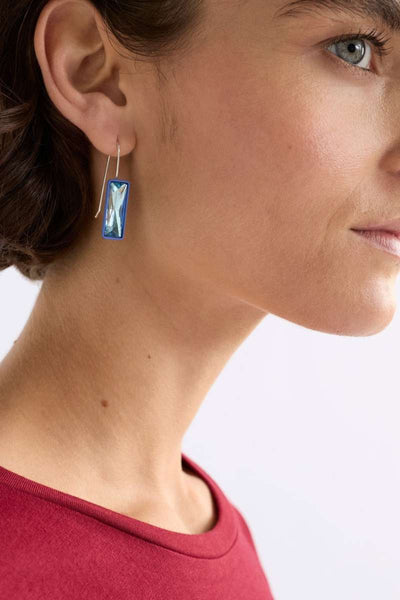 Close-up of a woman wearing blue earrings with a white background - Pair of blue earrings on a white background - Jule Small Hook Earrings by ELK. ELK Stockist at Newcastle, NSW at Zebra Finch