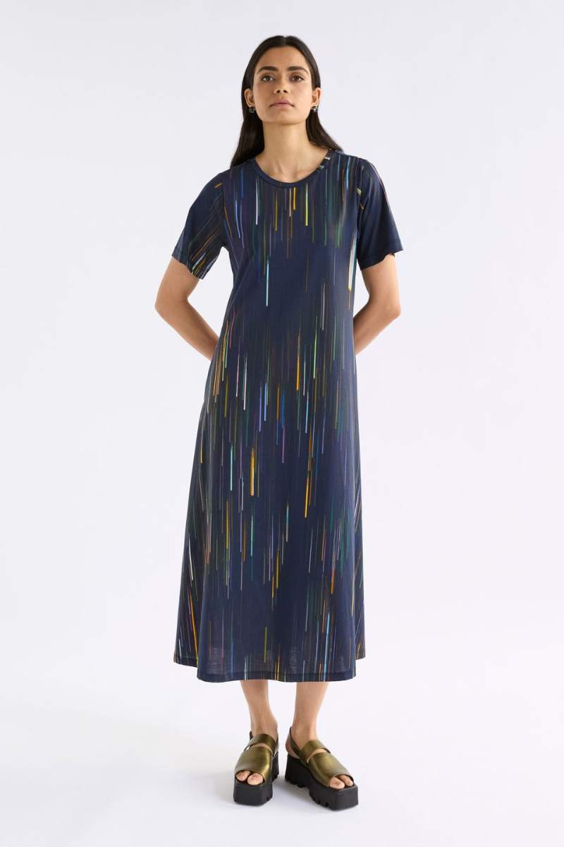 Woman wearing a navy dress with colourful vertical stripes on a white background
