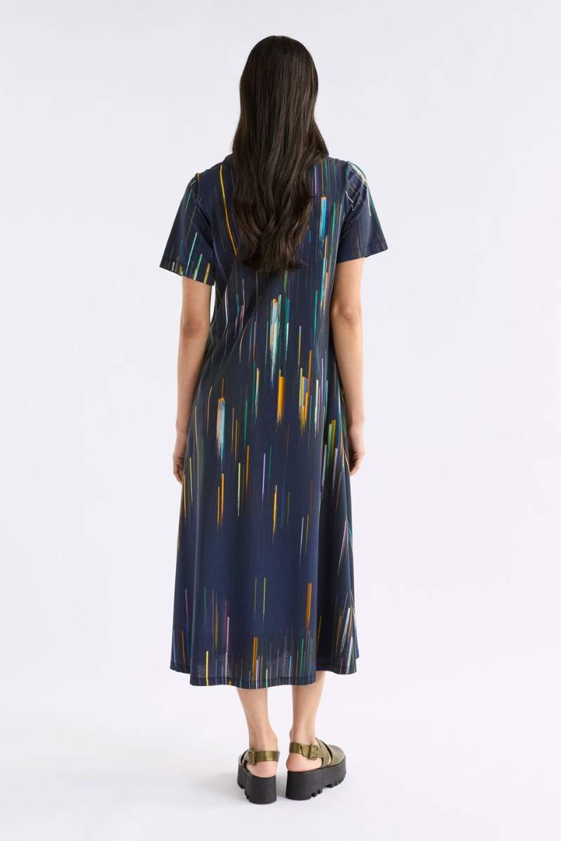 Woman wearing a navy dress with colourful vertical stripes on a white background
