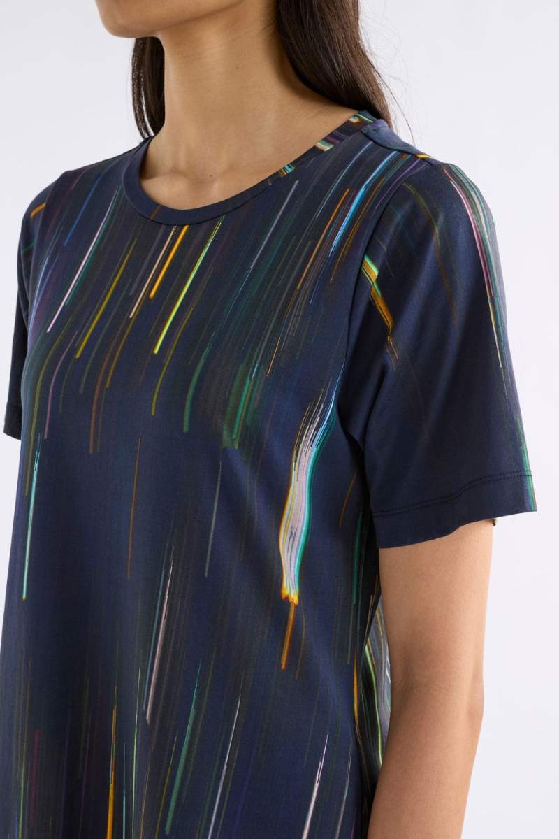 Woman wearing a navy dress with colourful vertical stripes on a white background