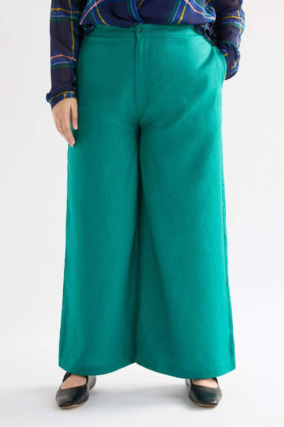 Person wearing teal wide-leg pants with a plaid shirt on a white background
