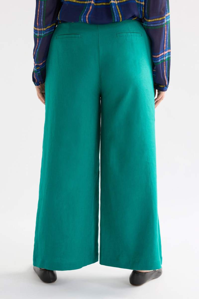 Teal wide-leg pants worn with a plaid shirt on a white background