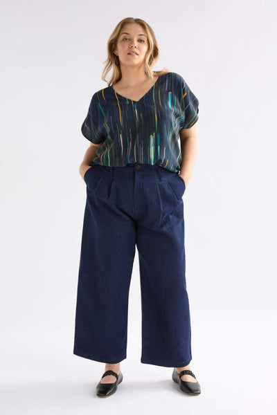 Woman wearing a patterned top and wide-leg pants on a white background