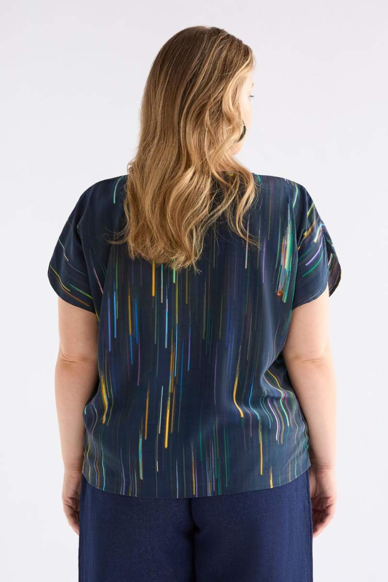 Person wearing a blue patterned top with short sleeves on a white background