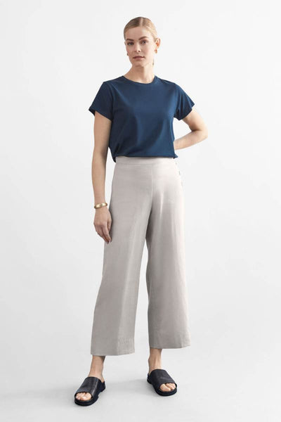 Woman wearing a blue top and light flax coloured pants on a white background y Elk the Label | Elk Stockist in Newcastle, NSW at Zebra FInch Style