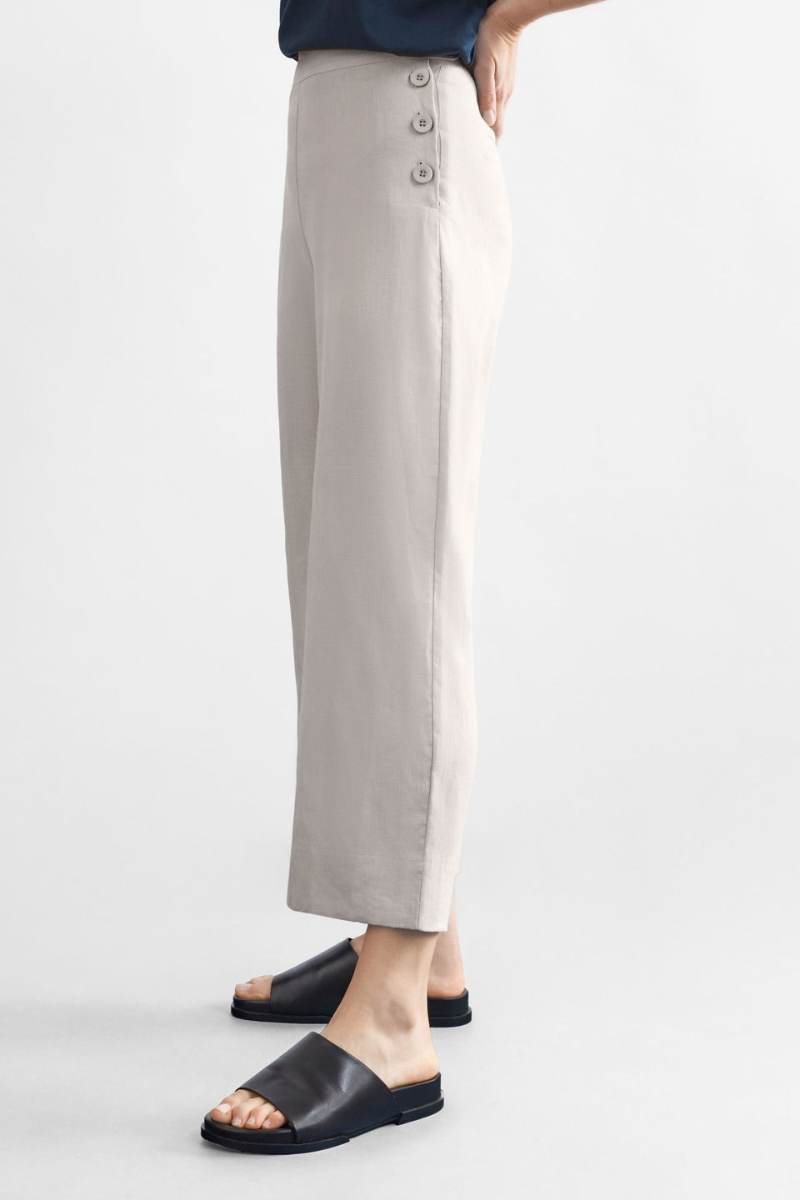 Woman wearing a blue top and light flax coloured pants on a white background y Elk the Label | Elk Stockist in Newcastle, NSW at Zebra FInch Style