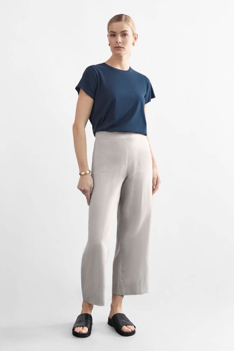 Woman wearing a blue top and light flax coloured pants on a white background y Elk the Label | Elk Stockist in Newcastle, NSW at Zebra FInch Style