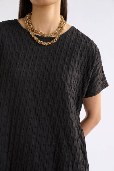 Person wearing a black textured top with a gold necklace on a white background Woman wearing a black textured top and orange pants on a white background by Elk the Label | Elk Stockist in Newcastle, NSW at Zebra Finch Style