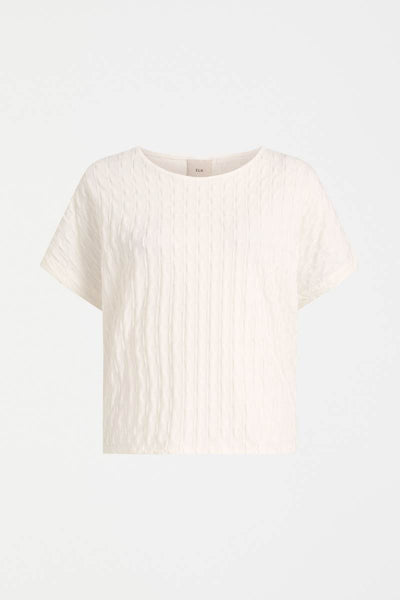 White textured t-shirt on a light gray background Woman wearing a white textured top and gray pants on a light background by Elk the Label | Elk Stockist in Newcastle, NSW at Zebra Finch Style