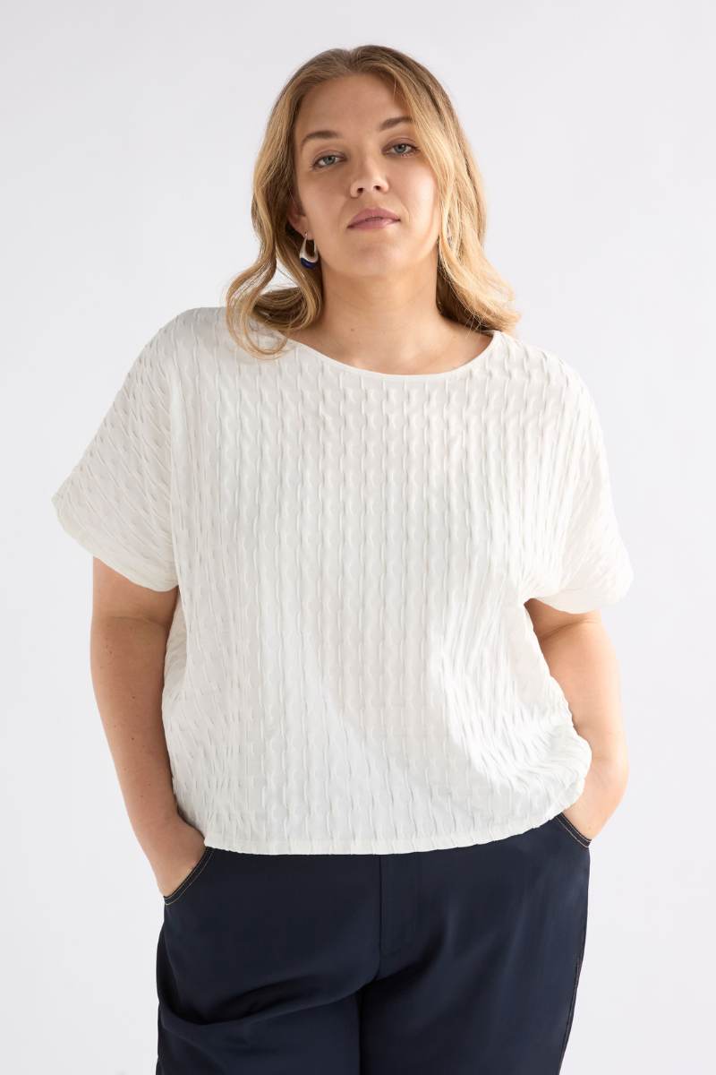 Woman wearing a white textured top and dark pants on a plain background Woman wearing a white textured top and gray pants on a light background by Elk the Label | Elk Stockist in Newcastle, NSW at Zebra Finch Style