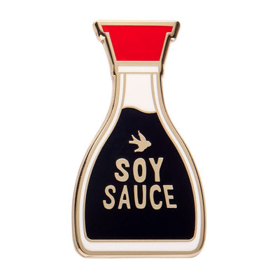 Pin shaped like a soy sauce bottle with red cap and black body on a white background. Erstwilder's soy sauce brooch from their 2025 condiments collection