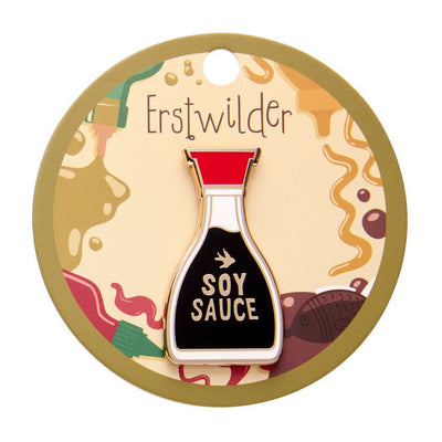 Pin shaped like a soy sauce bottle with red cap and black body on a white background. Erstwilder's soy sauce brooch from their 2025 condiments collection