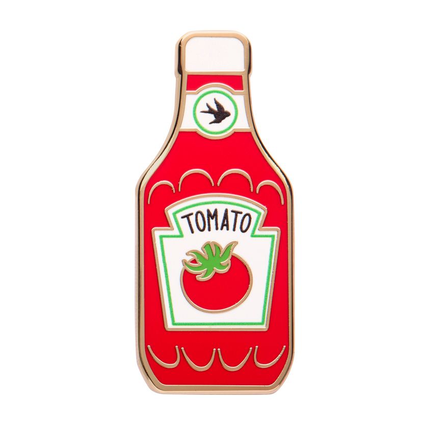 Enamel pin shaped like a tomato ketchup bottle with a logo on a white background. Erstwilder's Tomato sauce enamel pin from their 2025 Condiments collection