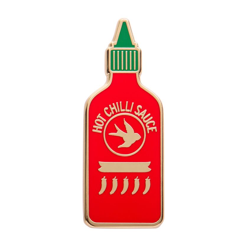 Hot chilli sauce bottle-shaped enamel pin with red body, green cap, and gold accents on a white background. Erstwilder's chilli enamel pin from their 2025 Condiments collection