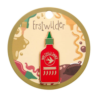 Hot chilli sauce bottle-shaped enamel pin with red body, green cap, and gold accents on a white background. Erstwilder's chilli enamel pin from their 2025 Condiments collection