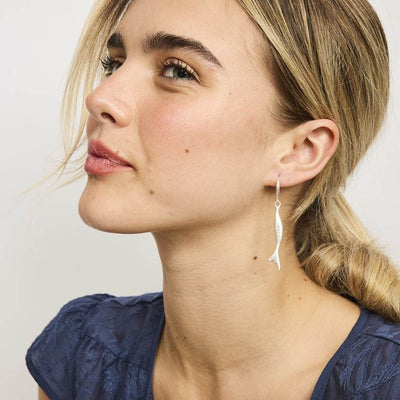 Close-up of a woman wearing a silver earring with a plain background