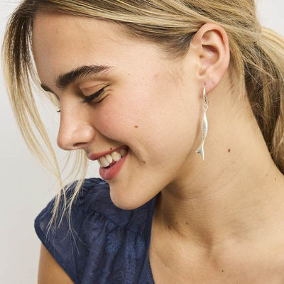 Woman wearing silver earrings with a plain background