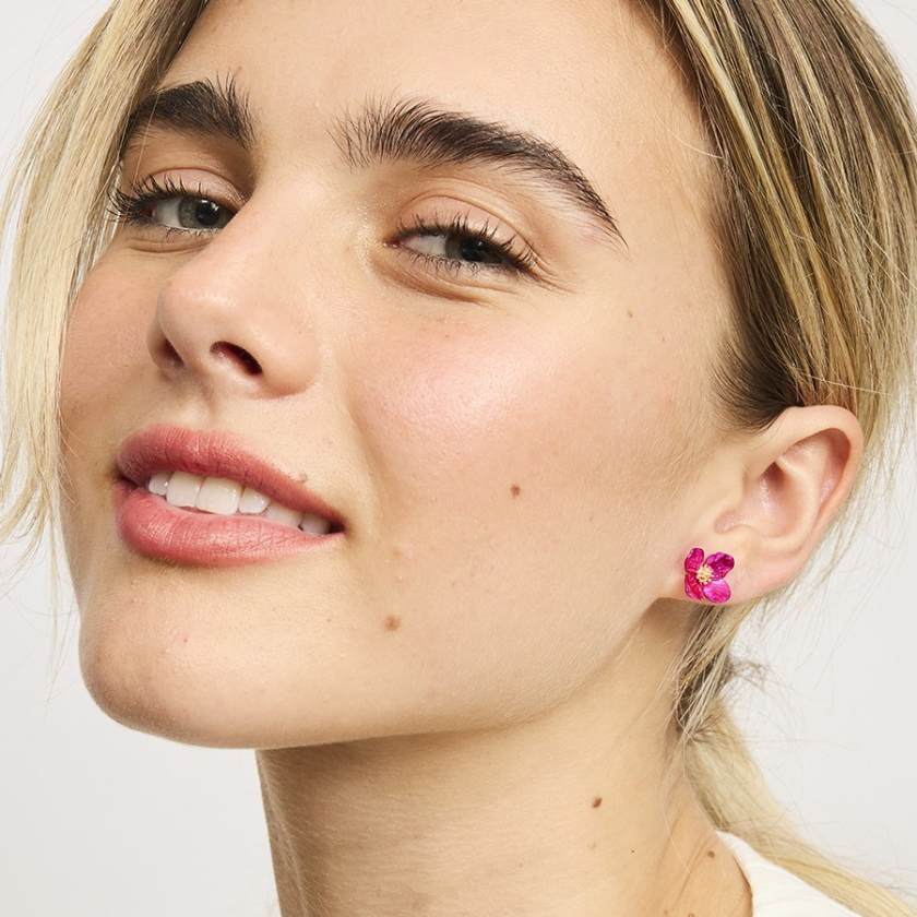 Close-up of a woman wearing pink flower earrings with a neutral background by Tiger Tree