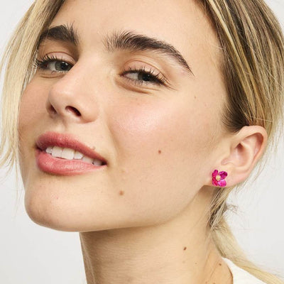 Close-up of a woman wearing pink flower earrings with a neutral background by Tiger Tree