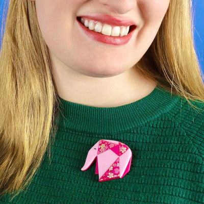 Forget me not pink elephant brooch on model's jumper by Erstwilder, from their 2023 Origami collection