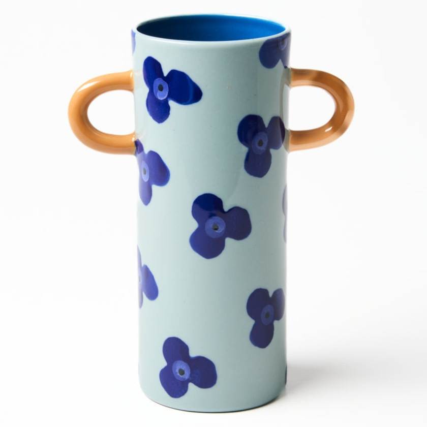 Cylindrical vase with blue floral patterns and brown handles on a white background