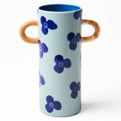 Cylindrical vase with blue floral patterns and brown handles on a white background