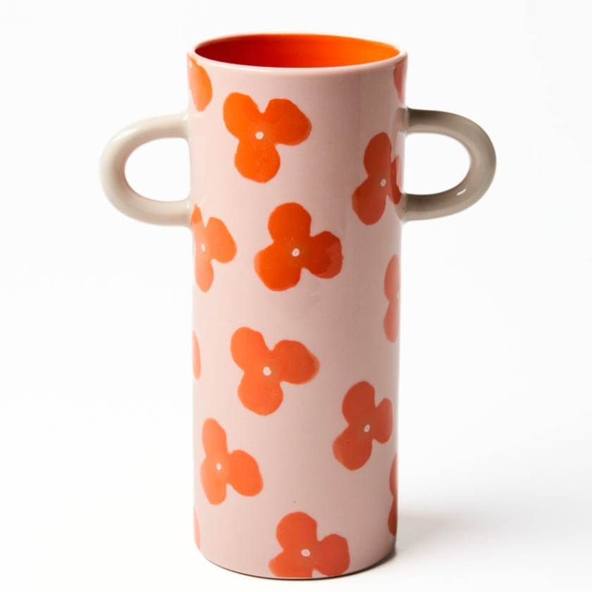 Cylindrical ceramic vase with orange floral patterns on a white background