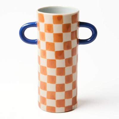 Cylindrical vase with orange and white checkered pattern and blue handles on a white background
