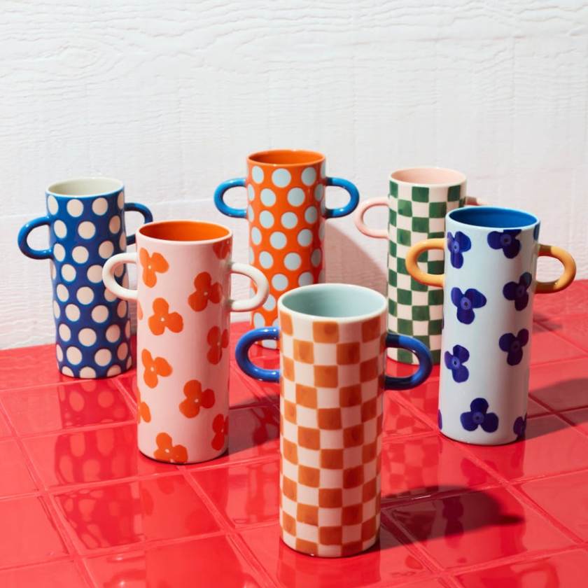 Colorful patterned vases on a red surface with a white textured background