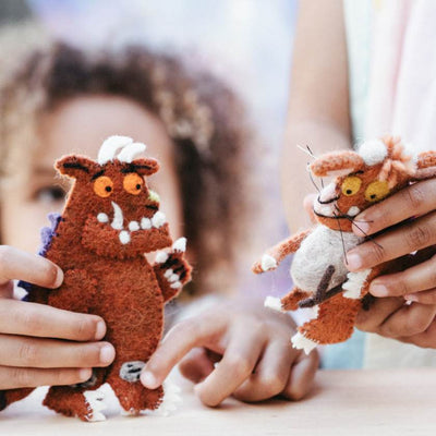 Two plush toys resembling characters from 'The Gruffalo' held by children.
