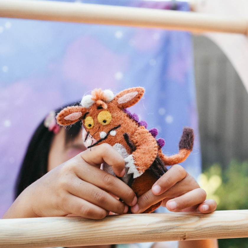 Child holding a small felt creature toy with a blurred background