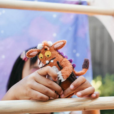 Child holding a small felt creature toy with a blurred background